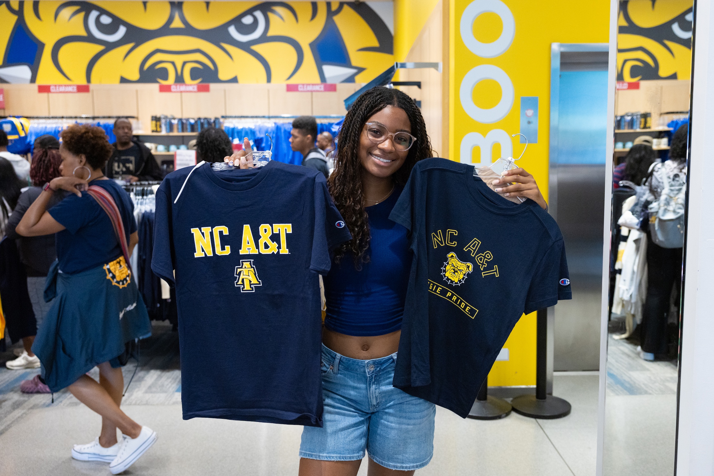 Student in bookstore holding A&T shirts