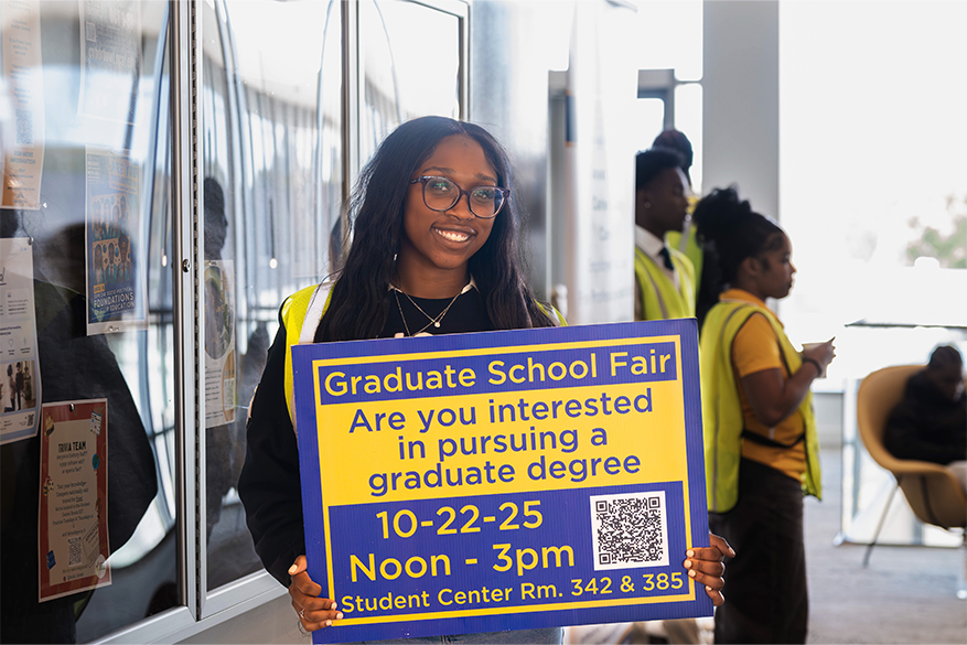 Student volunteer holding sign for 2025 Graduate Fair